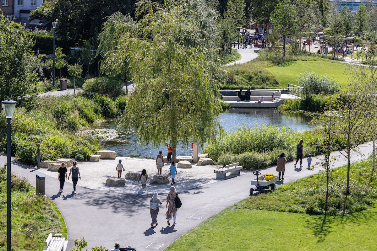 Visitors walking through Claremont Park on a sunny day in Brent Cross Town
