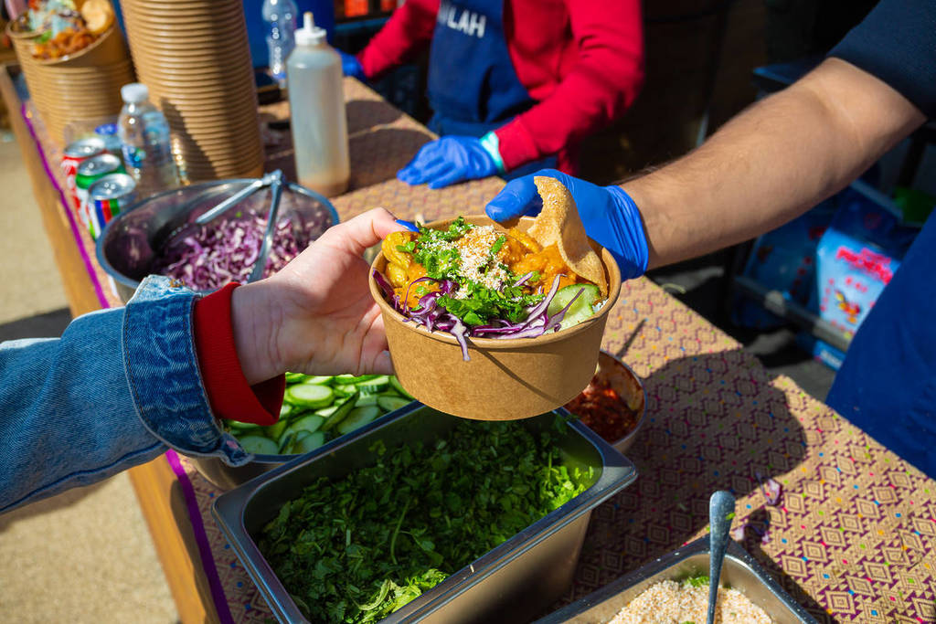jemand, der eine Schüssel mit südostasiatischem Streetfood überreicht