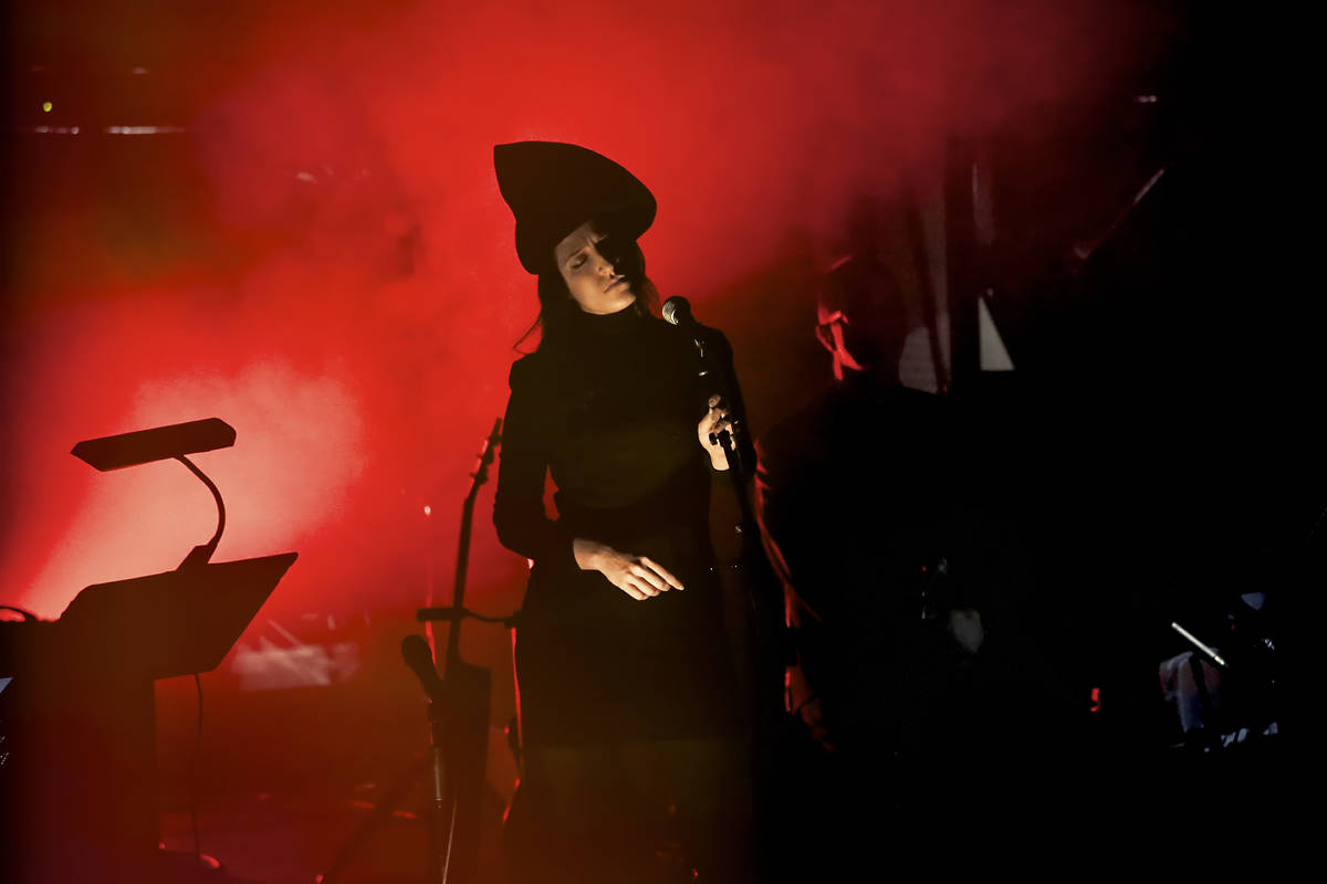 A woman dressed in black wearing a pointed hat holding a mic