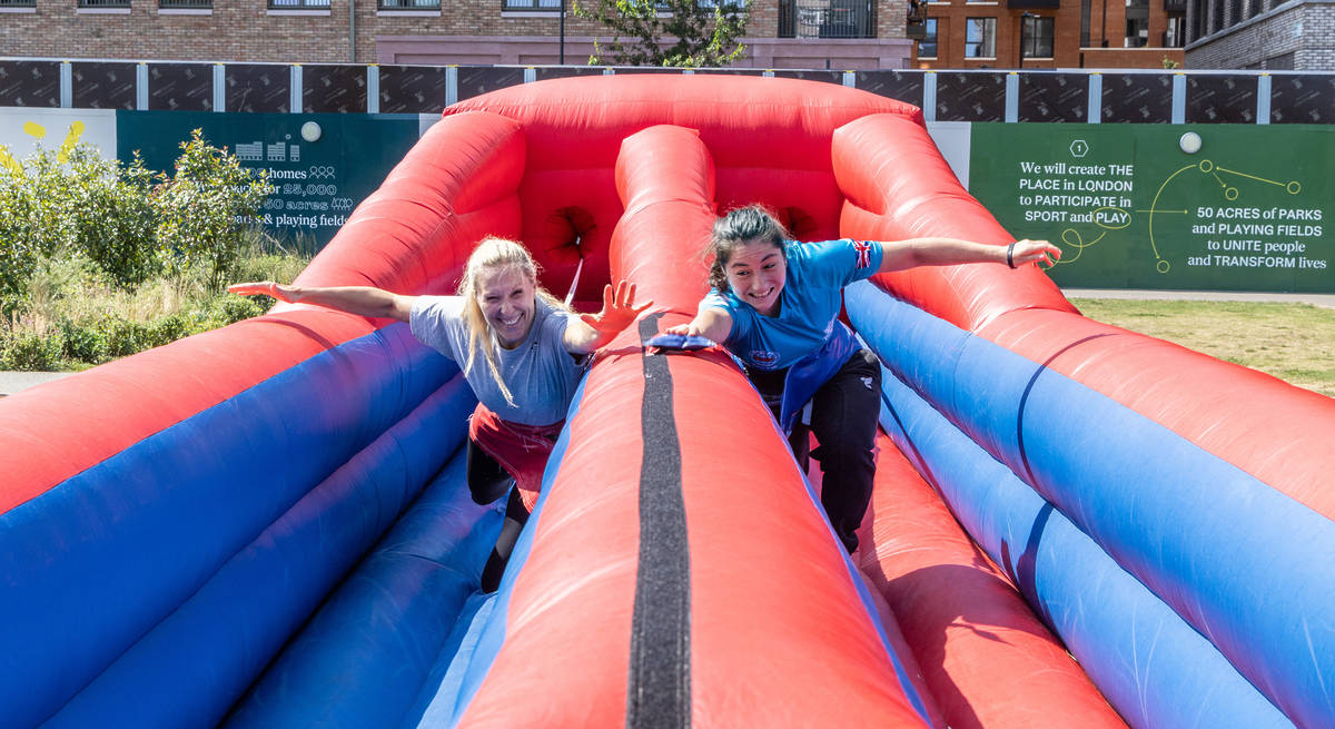 two people running along an inflatable obstacle course