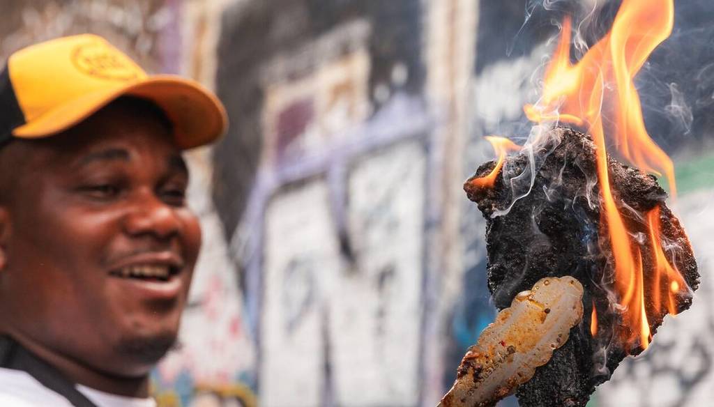 a BBQ pitmaster holding up a hunk of meat that is on fire