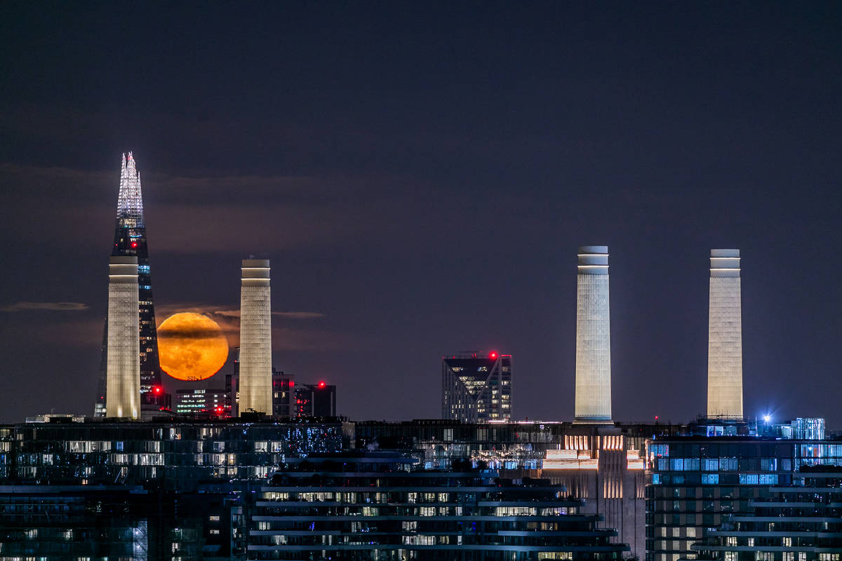a view of the moon amongst the london skyline at night