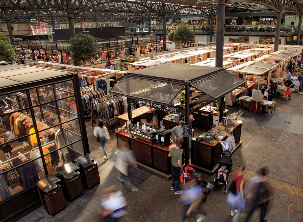 people wandering around Old Spitalfields Market, which is full of shopping stands and food stalls