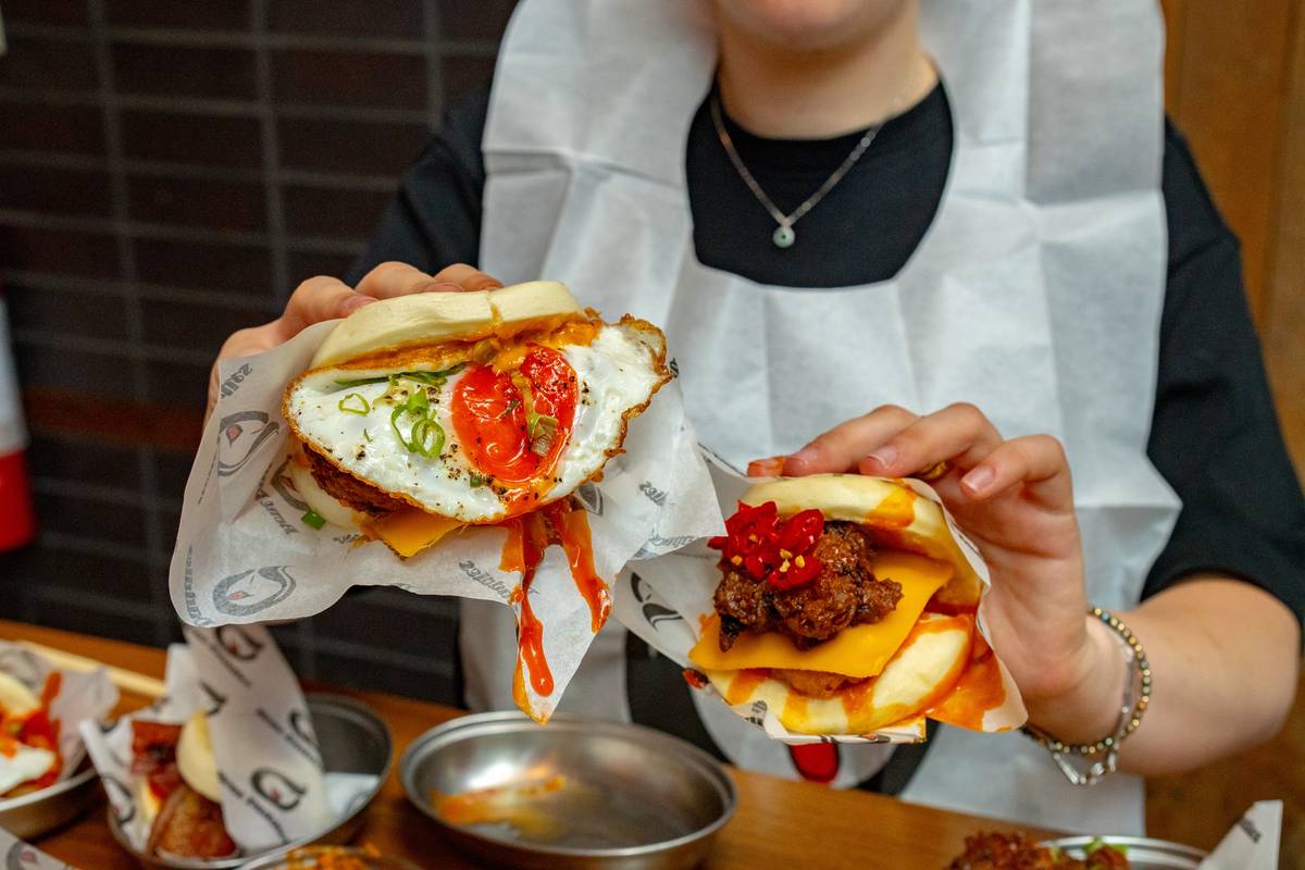 someone wearing a bib, holding up two enormous filled breakfast bao buns