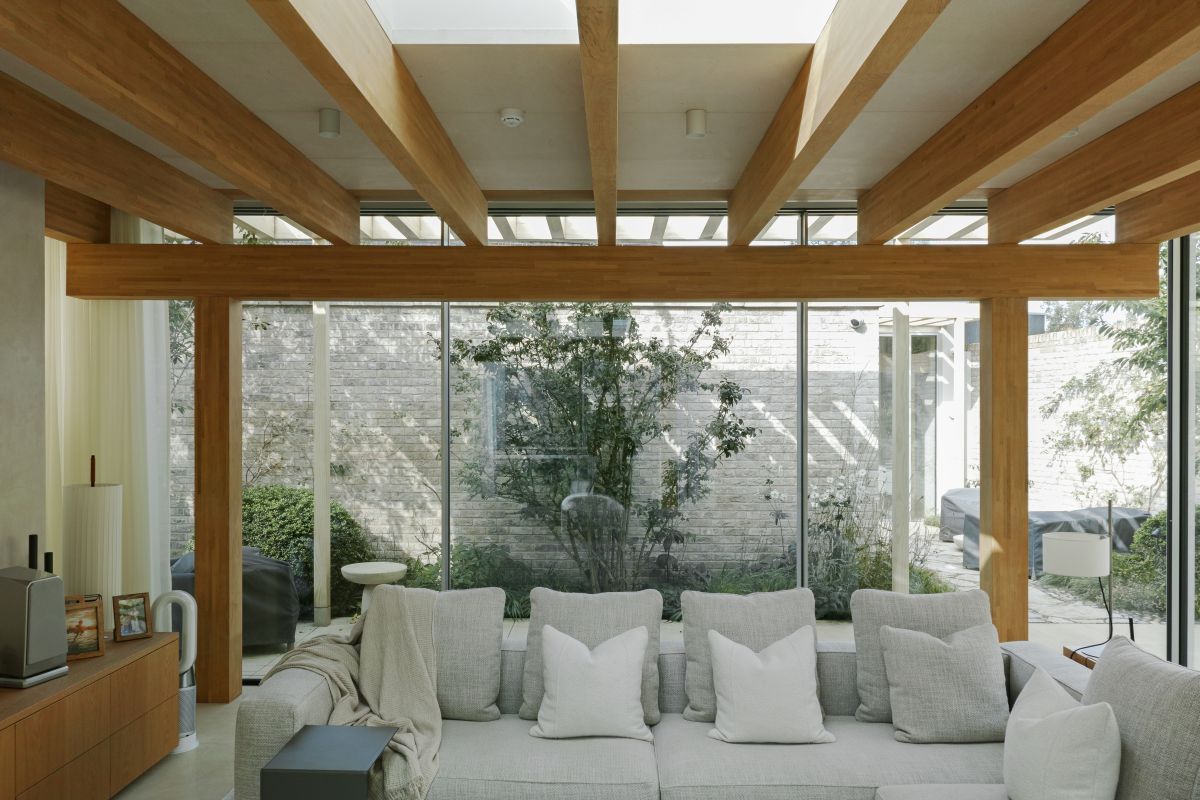 A sofa inside of Niwa House with floor to ceiling windows behind