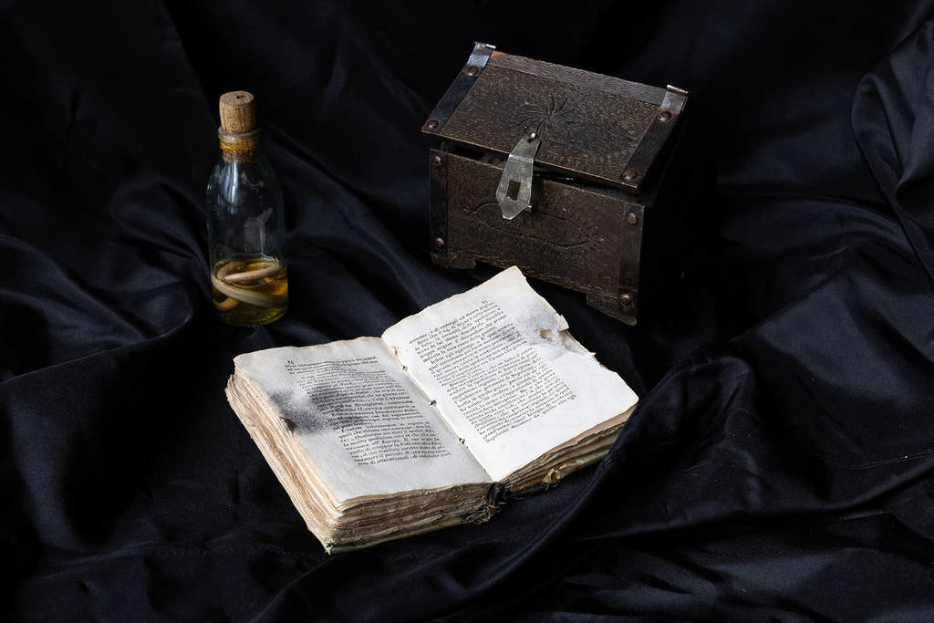 a selection of items - book, chest and glass vial - from the Dark Secrets exhibition