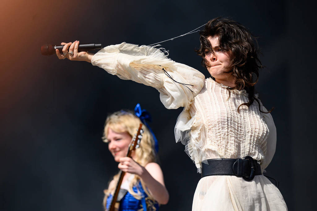 The Last Dinner Party on stage at Glastonbury 2024 with singer Abigail Morris pointing the microphone to the crowd