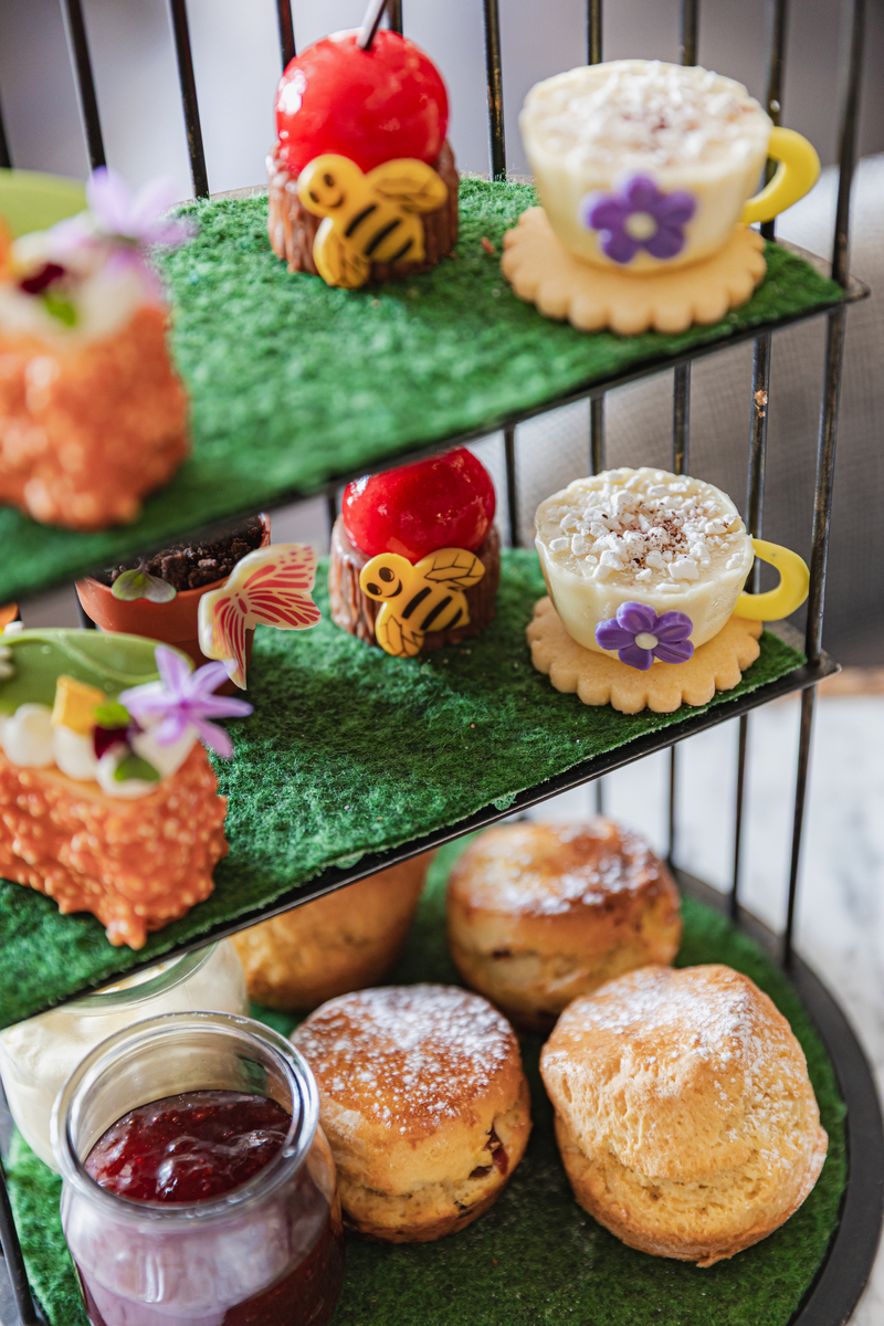 a selection of garden-themed foodstuffs arranged on a three-tier afternoon tea serving platter
