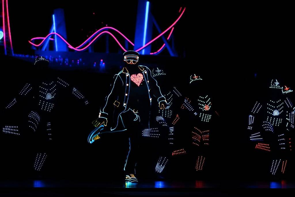 THE BLACKOUTS performing in LED-lit costumes on a dimly lit stage for Neon Moves