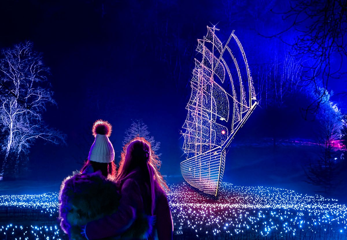 two people looking at a light installation recreating a pirate's ship in a park
