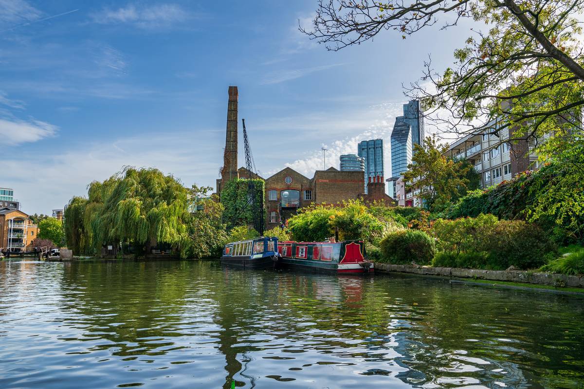 Some skyscrapers peeking out from behind the trees along Regent's Canal