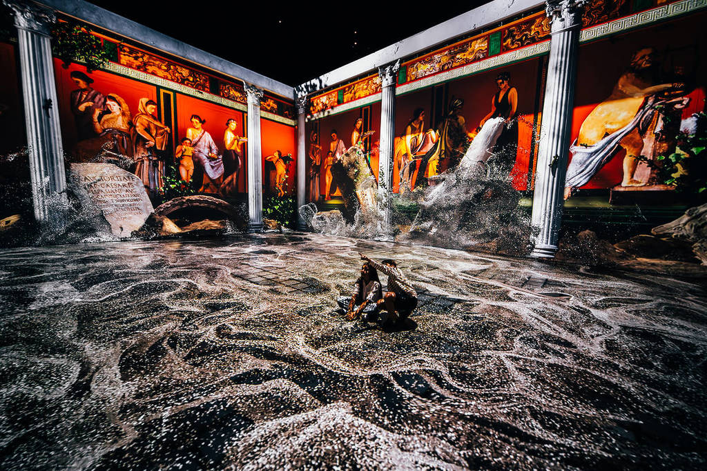 two people sit in a 360-degree show with projections of ash and ancient Roman life