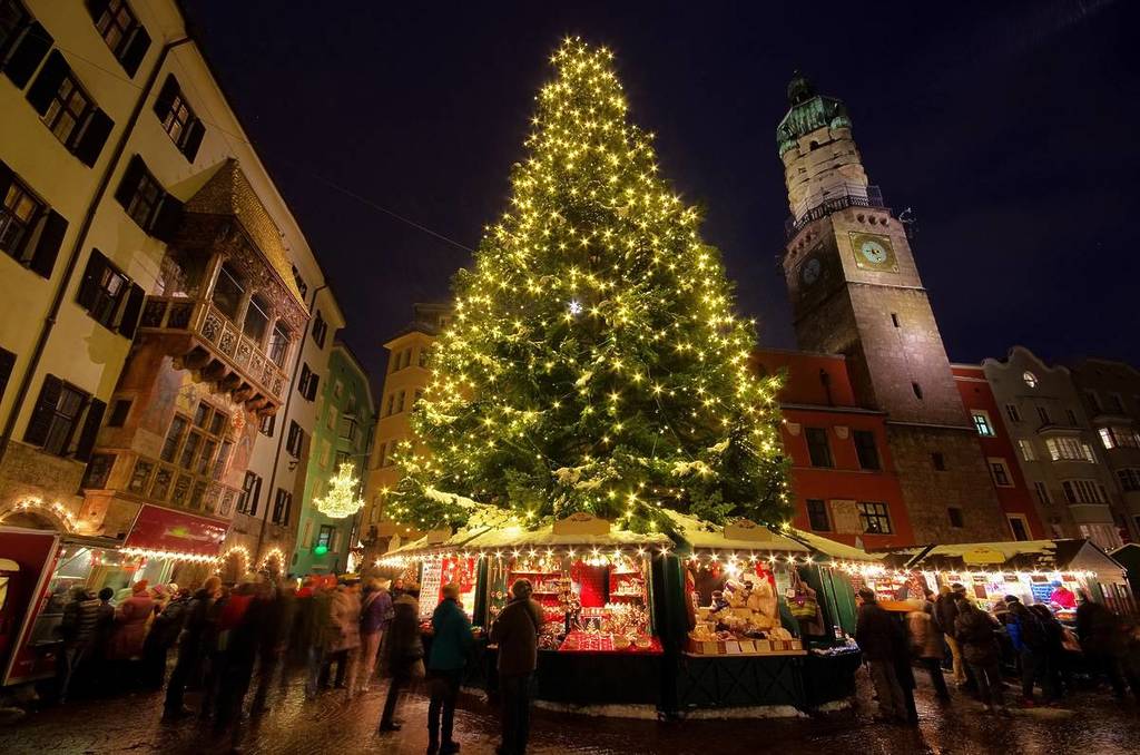 Marché de Noël de nuit avec un grand arbre de Noël illuminé entouré d'étals de marché