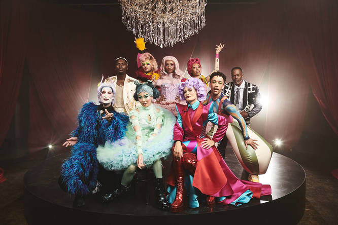 a cast of performer from a holiday show posing under a chandelier
