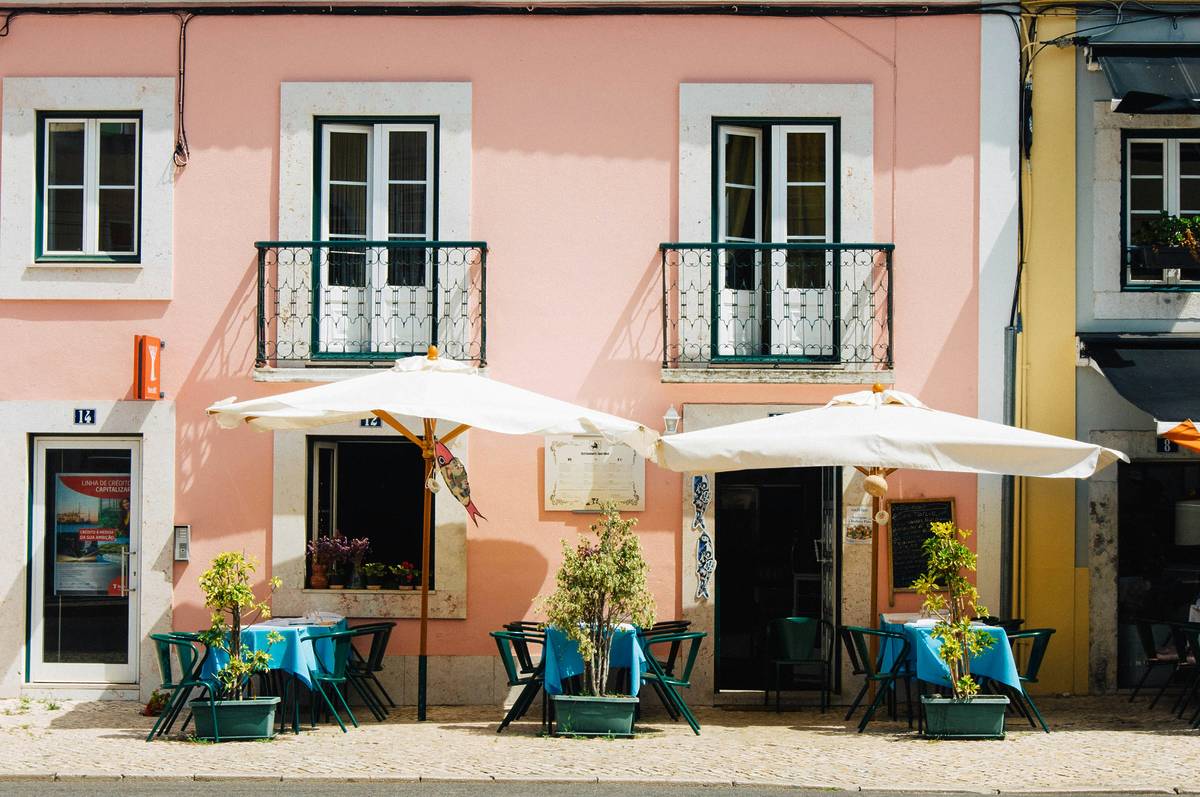 two white patio umbrellas near pink and white painted concrete building in Lisbon