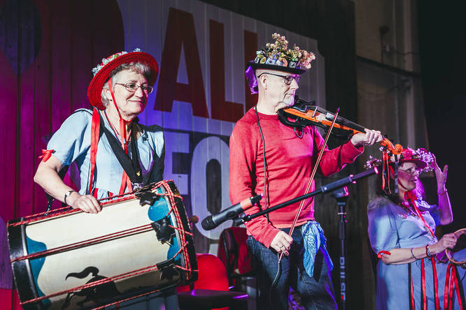 Members of a band with a big drum and violin vibing out on stage