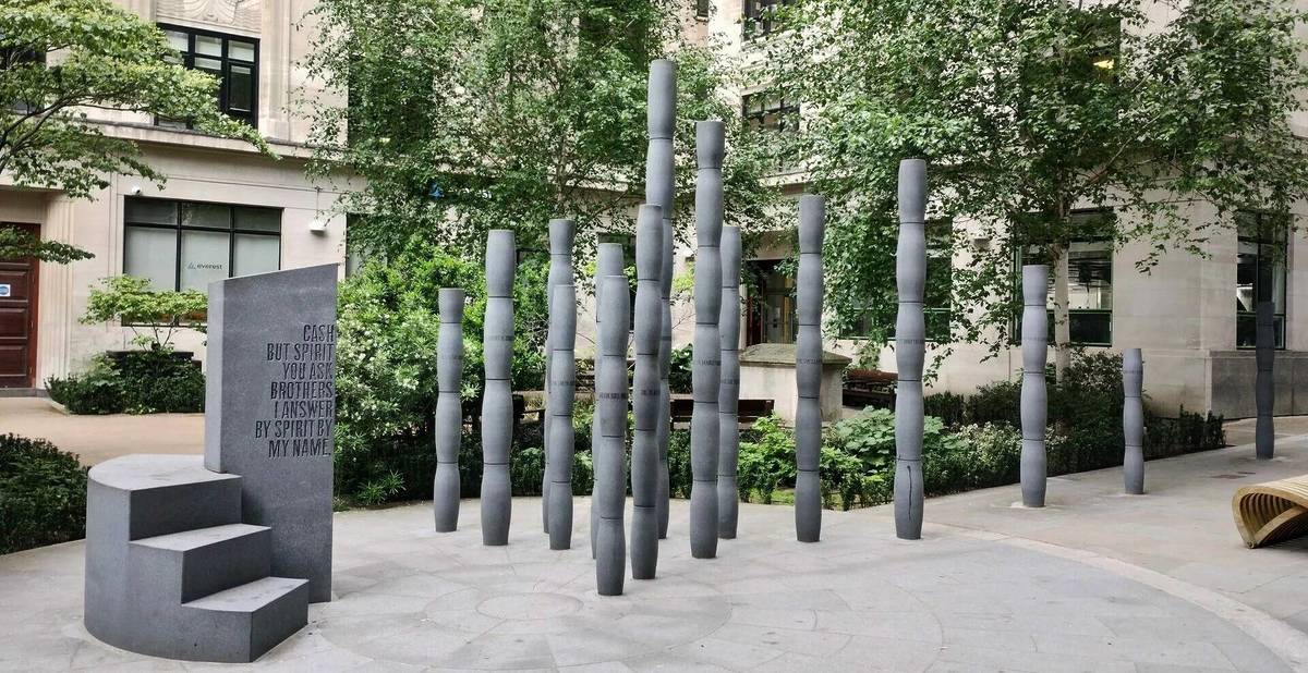 a simple sculpture of tall columns and a plinth with poetry etched into it