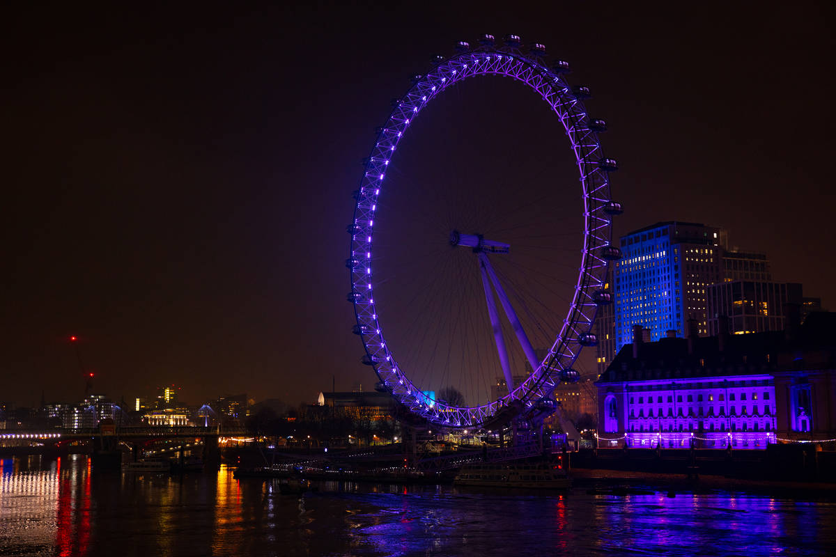 the london eye seen at night lit up in purple