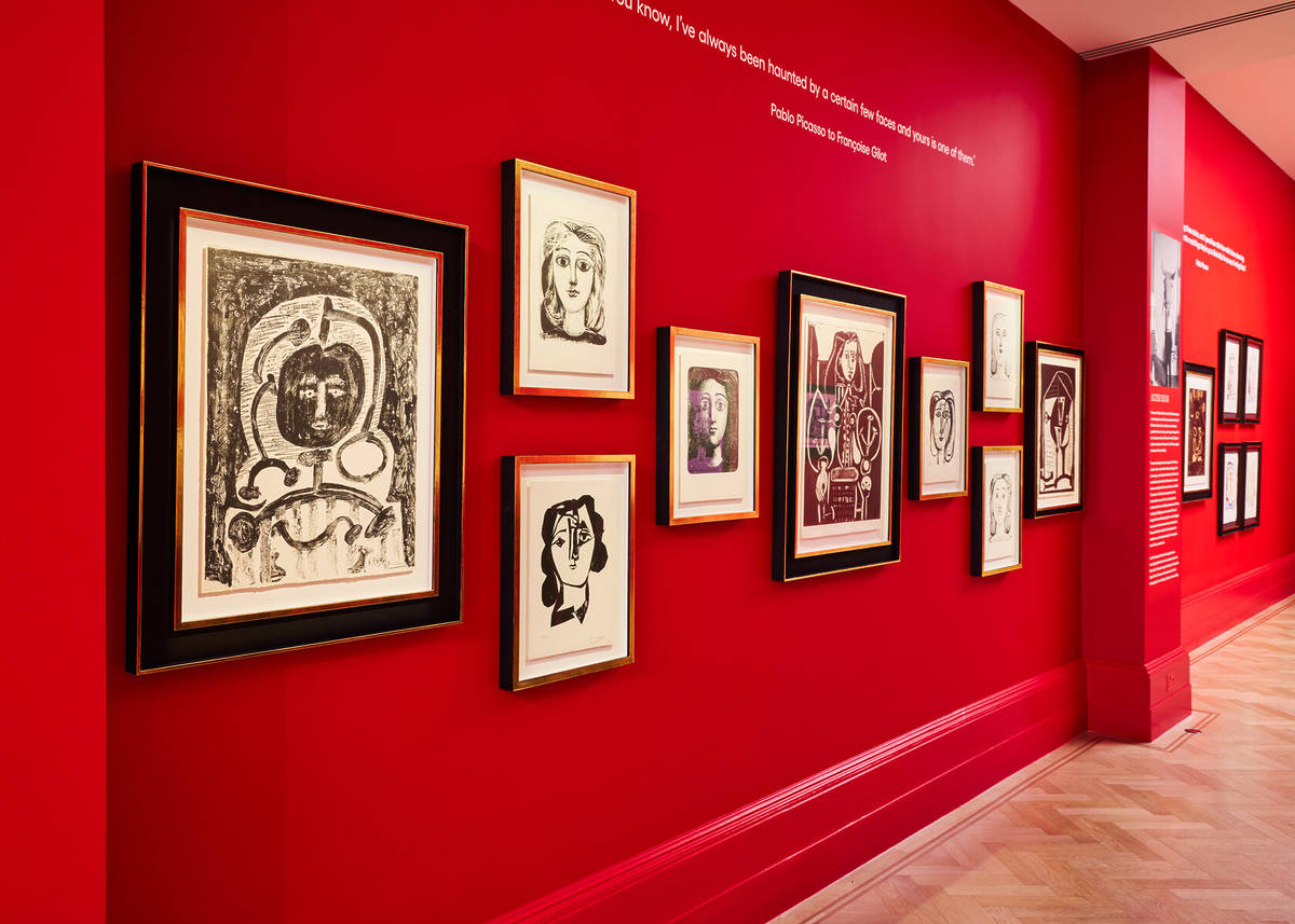 a red wall adorned with multiple artworks by pablo picasso