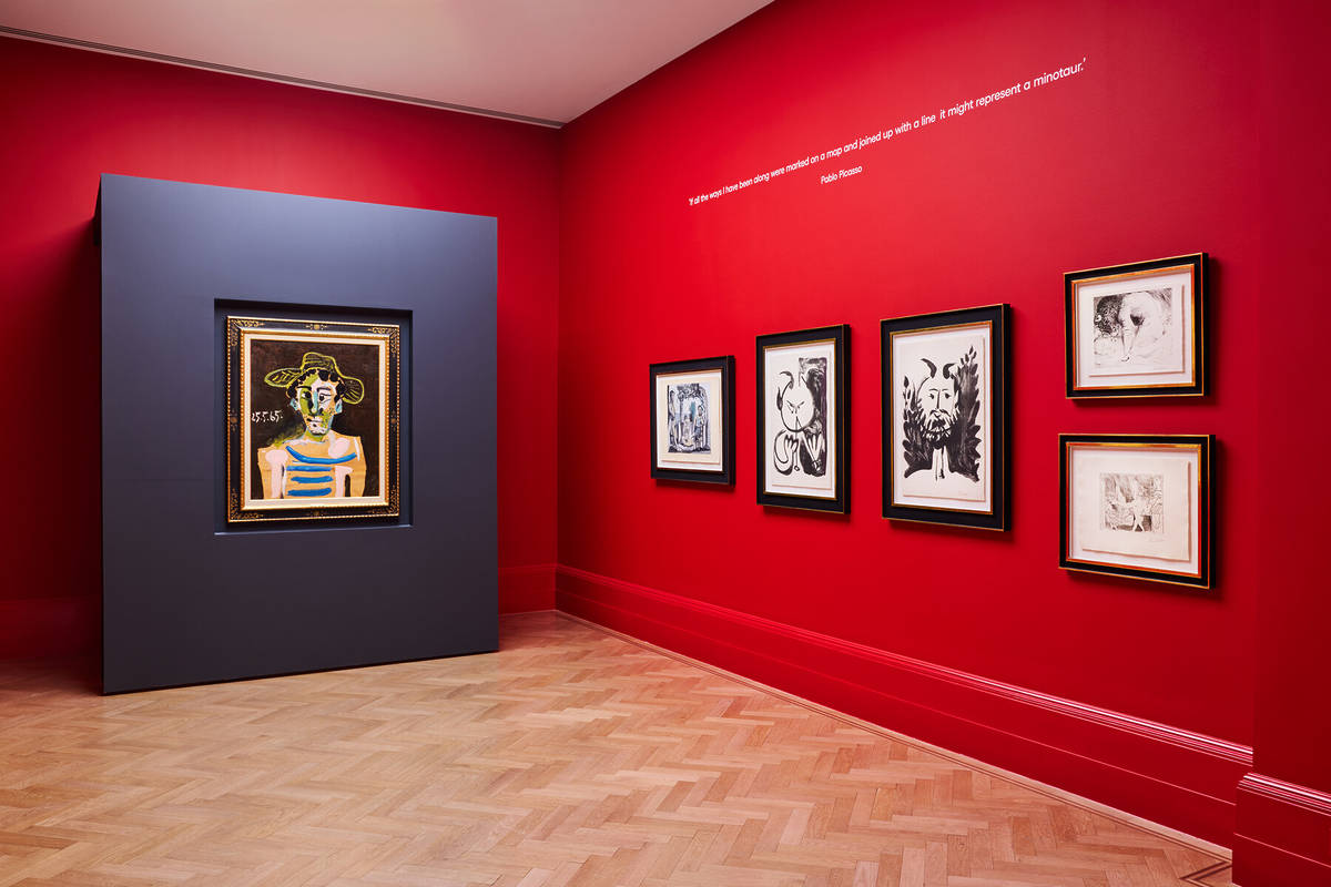 a red wall adorned with multiple artworks by pablo picasso next to a striking blue wall with a single piece of art on it