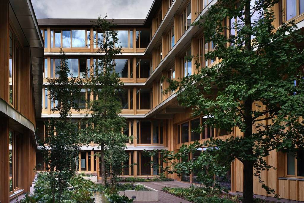 Un edificio con molte finestre a forma di U intorno a un cortile alberato