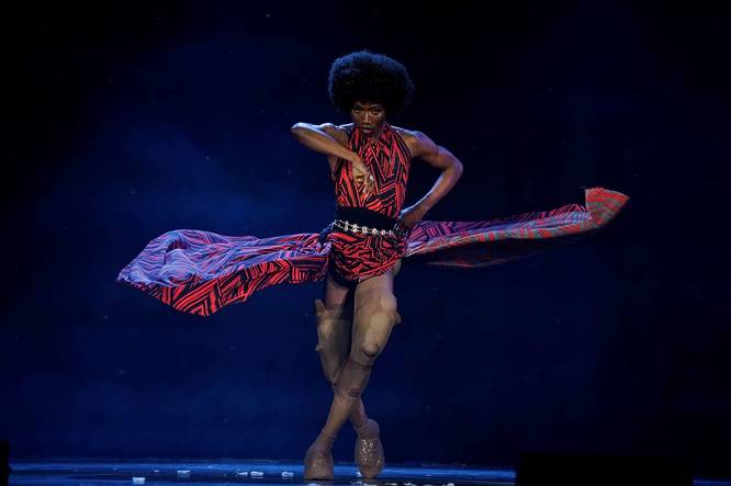 A performer mid-dance on stage, skirt flaring outward