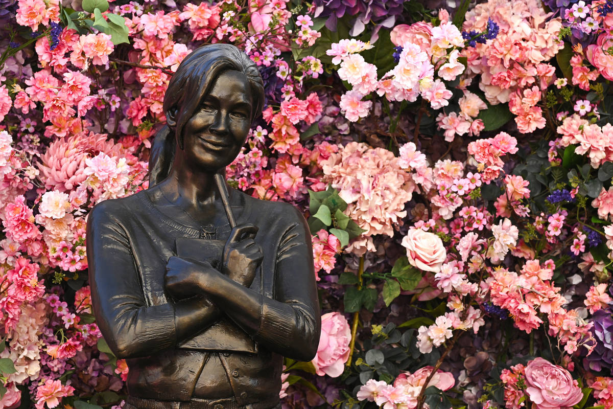 a statue of iconic rom-com character bridget jones presented in front of a floral display