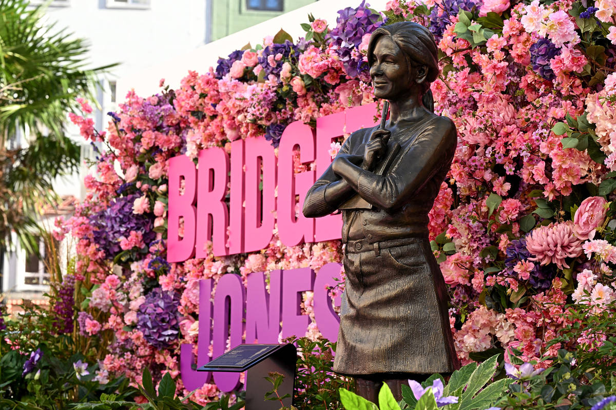 a statue of iconic rom-com character bridget jones presented in front of a floral display and the words 'BRIDGET JONES'