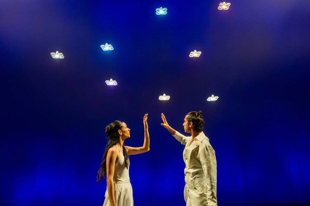 Zwei Tänzer berühren sich vor einem Himmel voller leuchtender Drohnen beim Dance of Drones.
