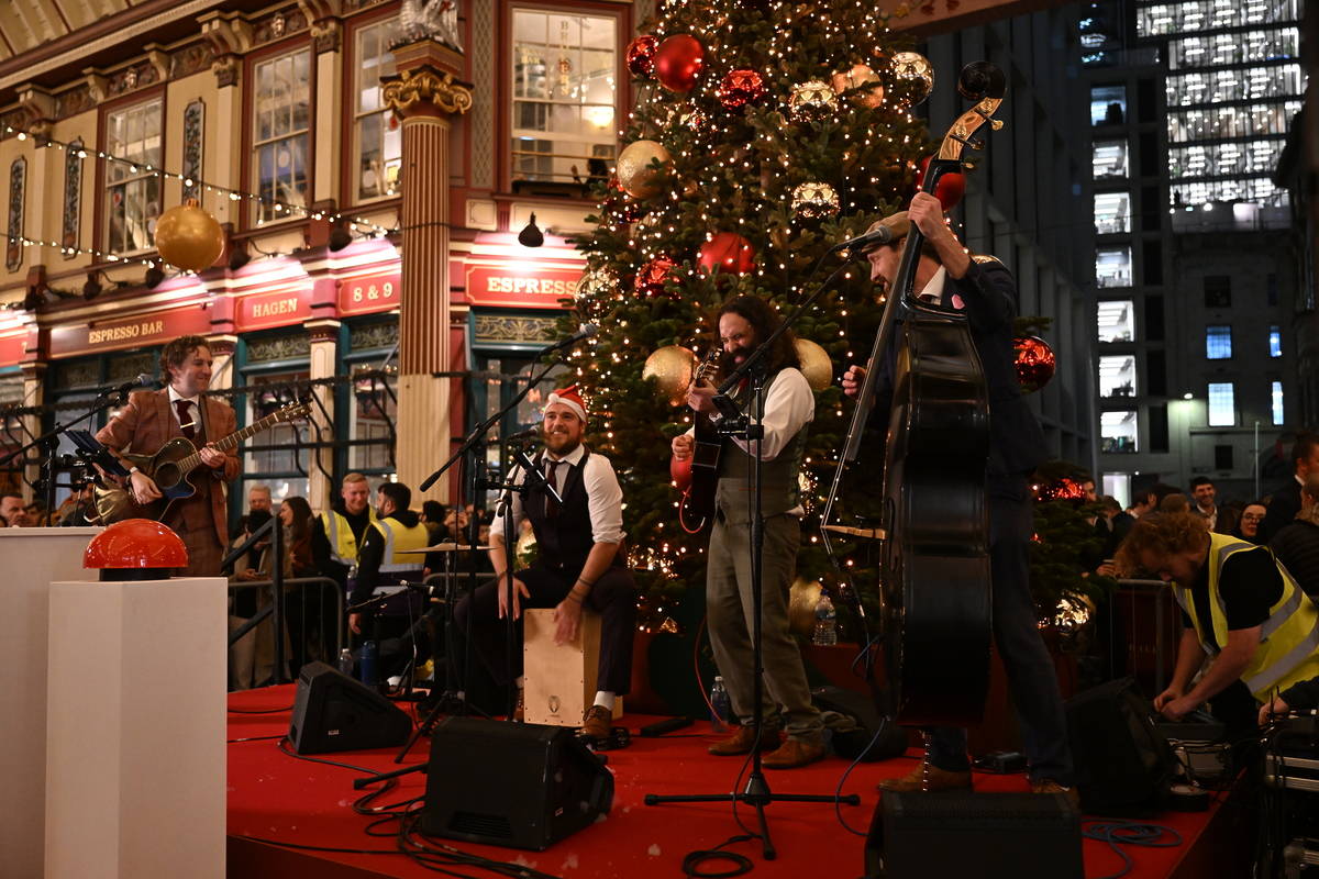 performers in santa hats on stage in front of the leadenhall market chrsitmas tree