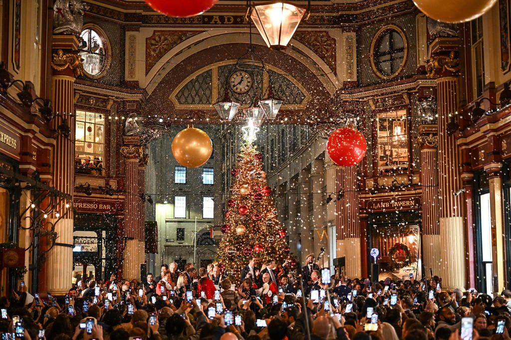 una folla di persone che scatta foto all’albero di Natale illuminato del Leadenhall Market