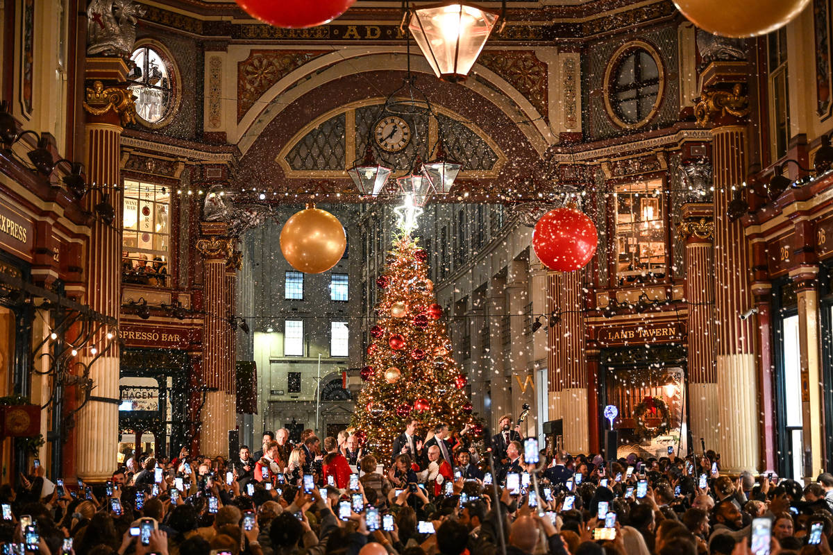 a crowd of people taking photos of the illuminated leadenhall market christmas tree