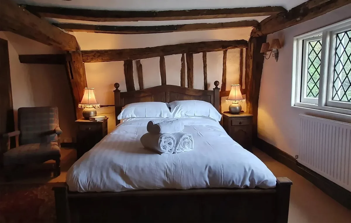 A bedroom with dark wooden furniture and white bedsheets