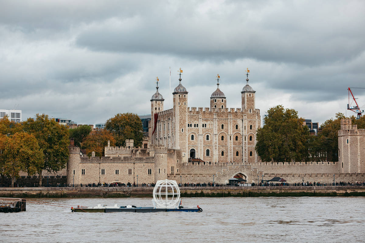 a large cage on a barge floating down the thames past the tower of london