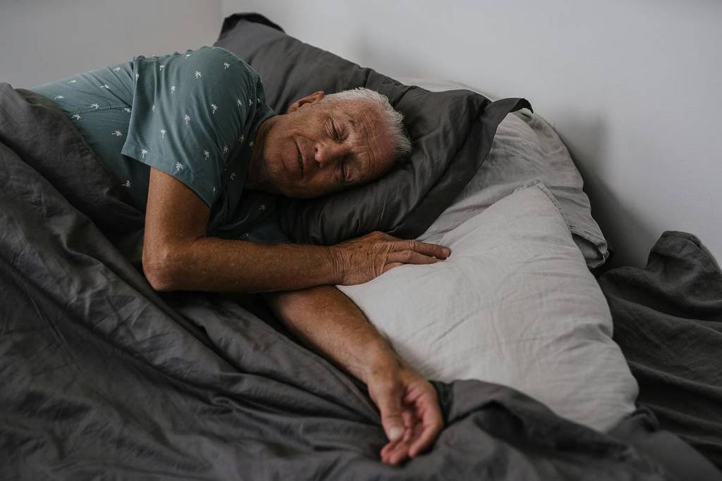 Un homme âgé qui dort sur le lit
