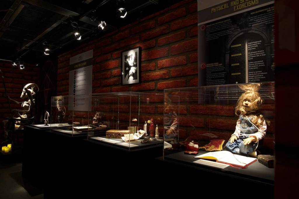 a series of cabinets with creepy dolls and other items relating to exorcisms at the Dark Secrets exhibition
