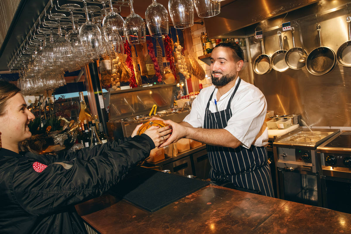 the chef in an italian restaurant kitchen accepting a pumpkin from a guest