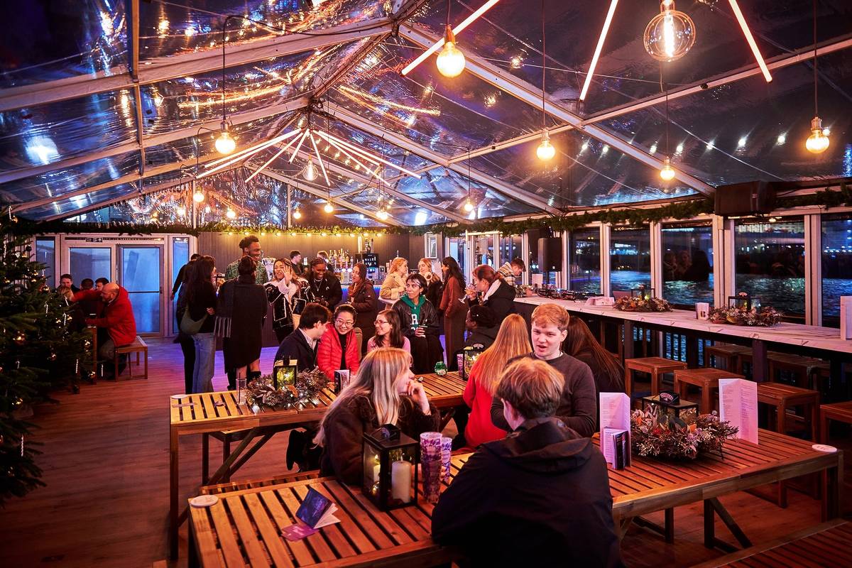 people sat at tables enjoying warming drinks in a covered bar area