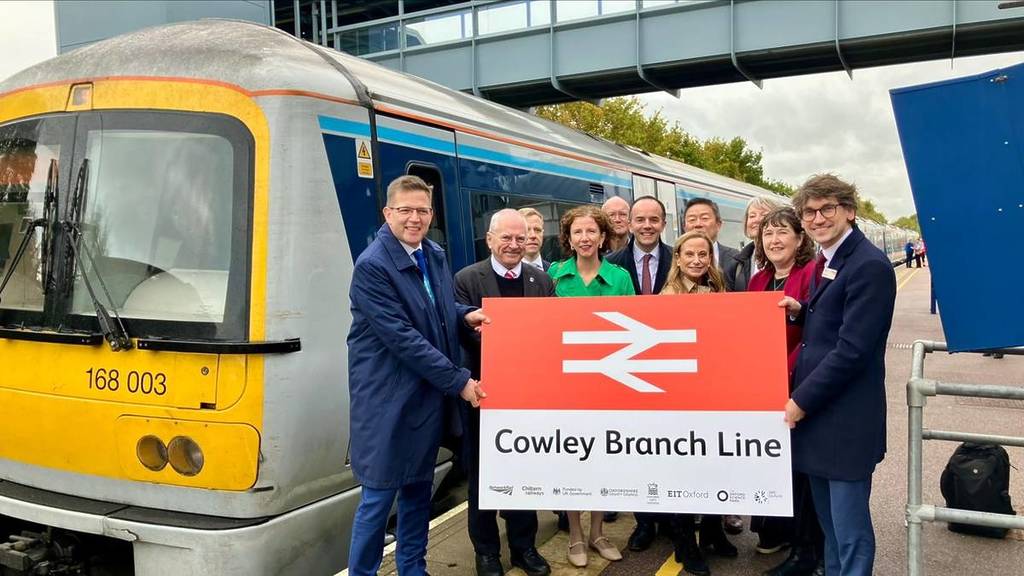 Het Network Rail team houdt het bord omhoog voor de binnenkort te heropenen Cowley Branch Line