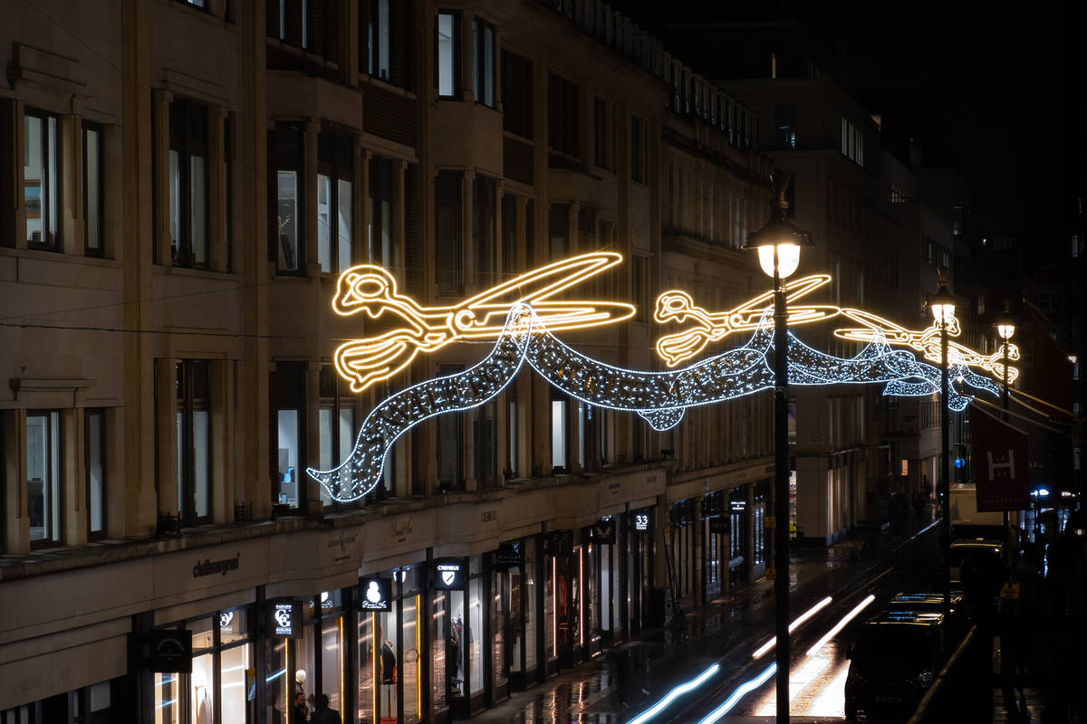 a shimmering christmas light display above savile row showing golden shears cutting through 'fabric'