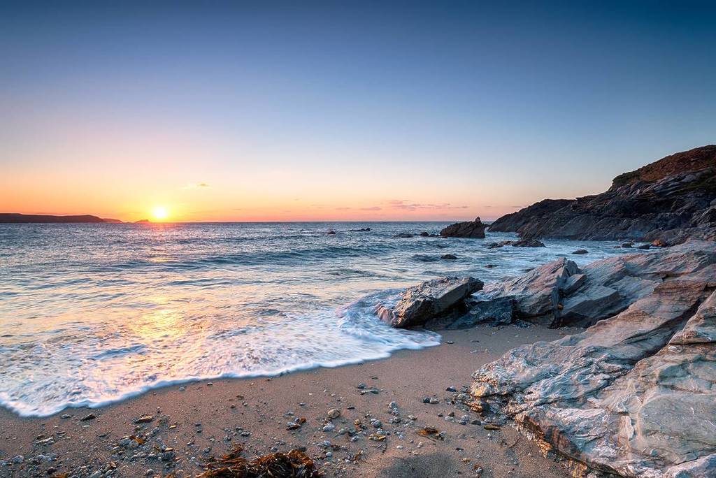 Water flowing onto the sad on a beach in Newquay at sunset