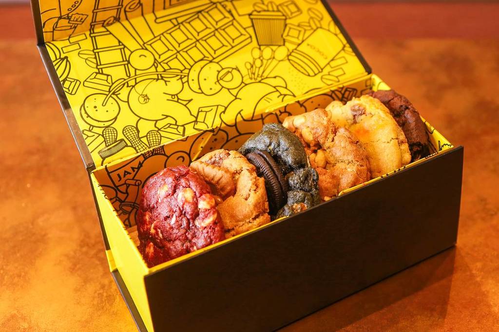 a box with a yellow patterned interior filled with chunky cookies in a variety of flavours