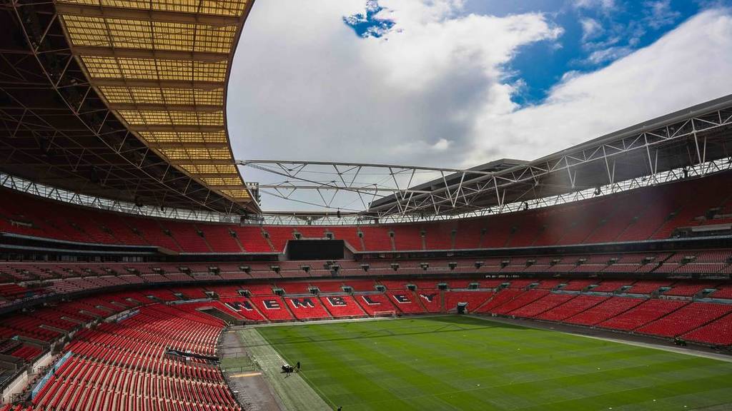 Shot from inside Wembley stadium, lots of red chairs with chairs in black spelling out 