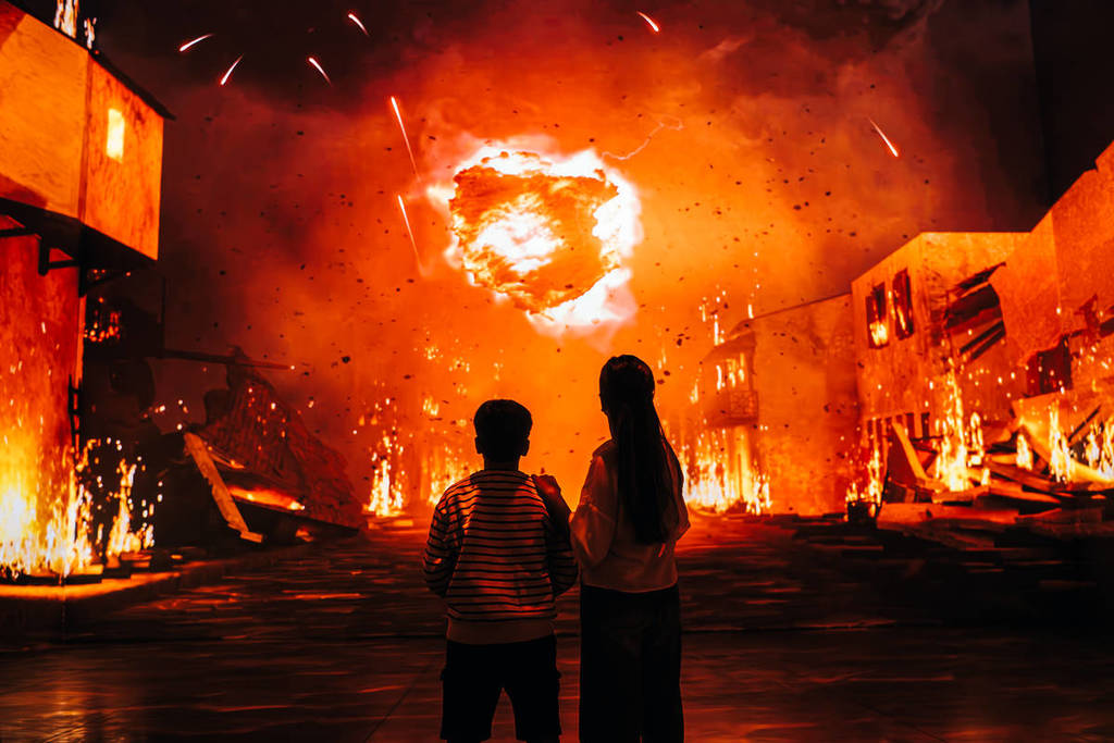 two people watch a volcanic bomb hurtle through the sky on a 360-degree projection at The Last Days of Pompeii: The Immersive Exhibition