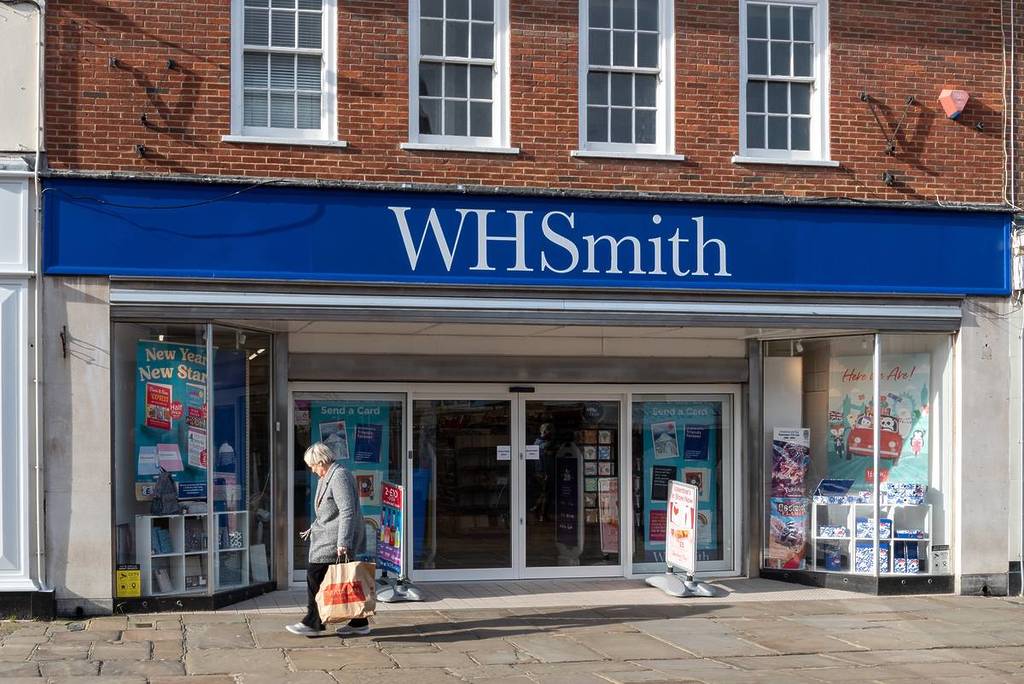 Chichester, England. January 28th 2024. Front entrance to a WH Smith store with a passer by walking in front.