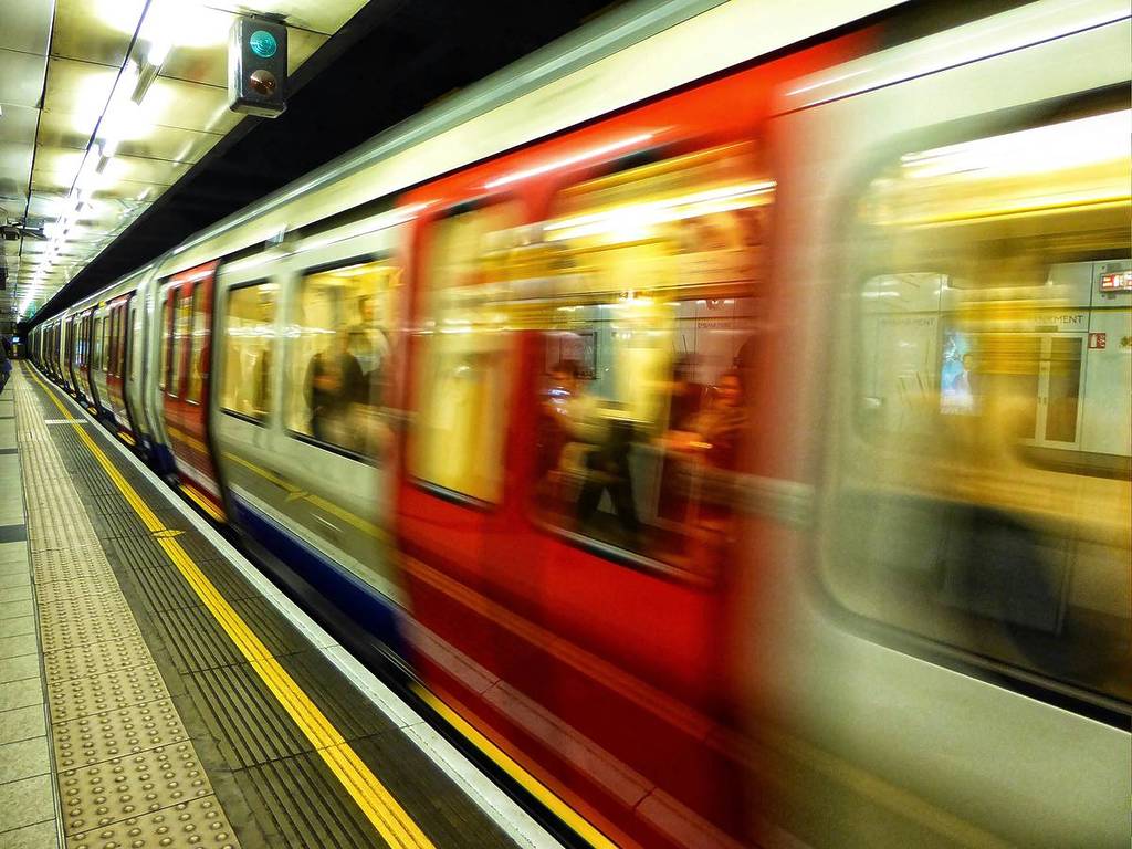 Blurred image of a red and white tube train moving through a platform