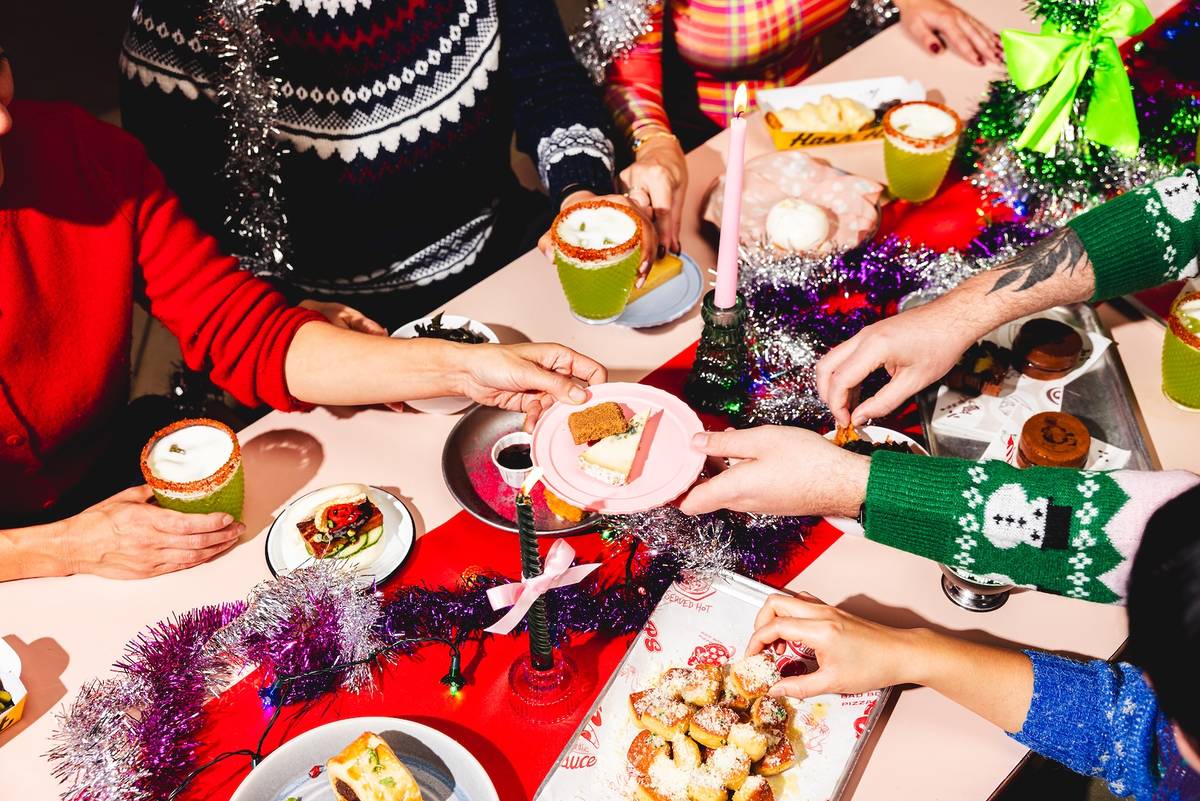 people clad in festive jumpers grabbing food of the table at Seven Dials Market's pick bits Christmas dinner