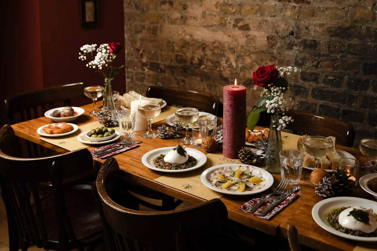 a festive dining table spread with food and red pillar candles