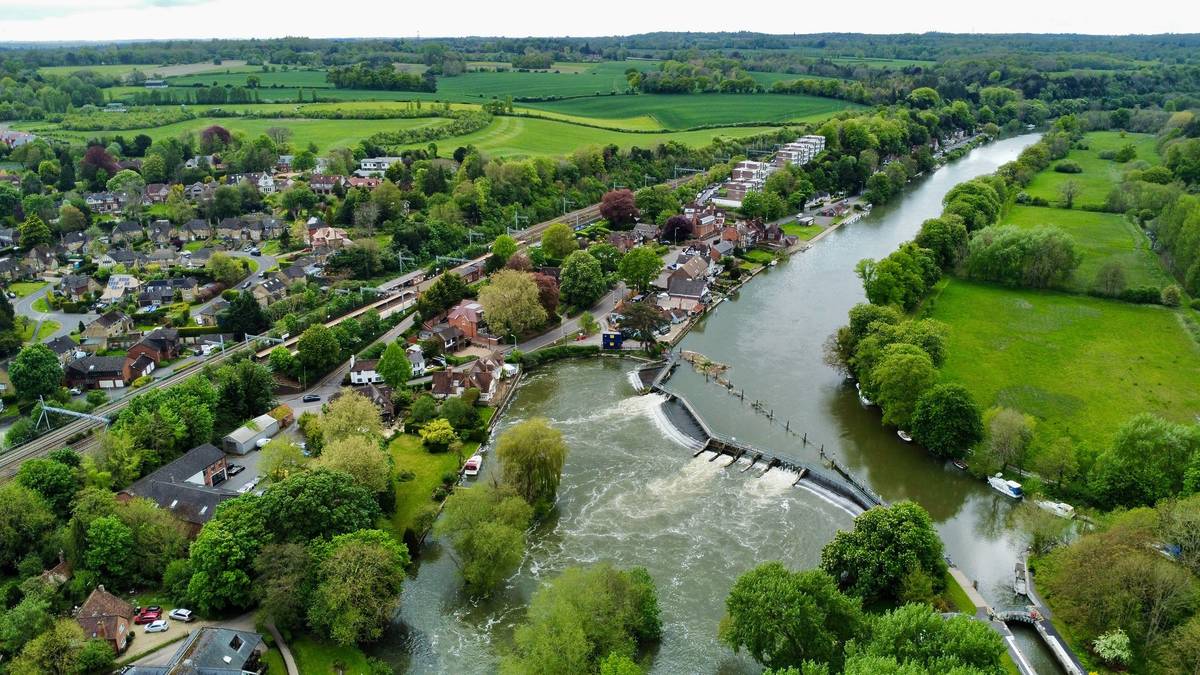 An aerial view of Pangbourne village with a river running thorugh it