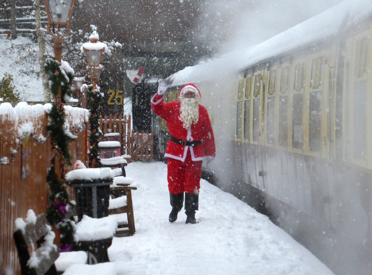 Somebody dressed as Santa stood next to a vintage train